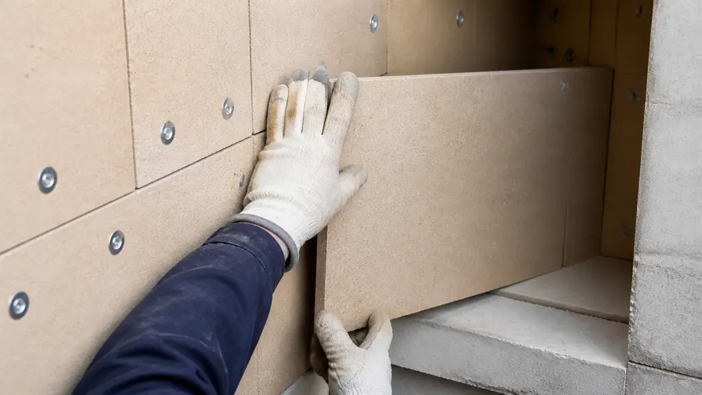 close-up of refractory underlay boards being fitted inside an industrial furnace wall, showing staggered joints, clean corner cuts and visible mechanical fasteners